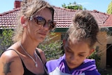 Denishar Woods' mother Lacey Harrison and sister Anita Woods stand outside their Beldon home holding a white teddy bear.