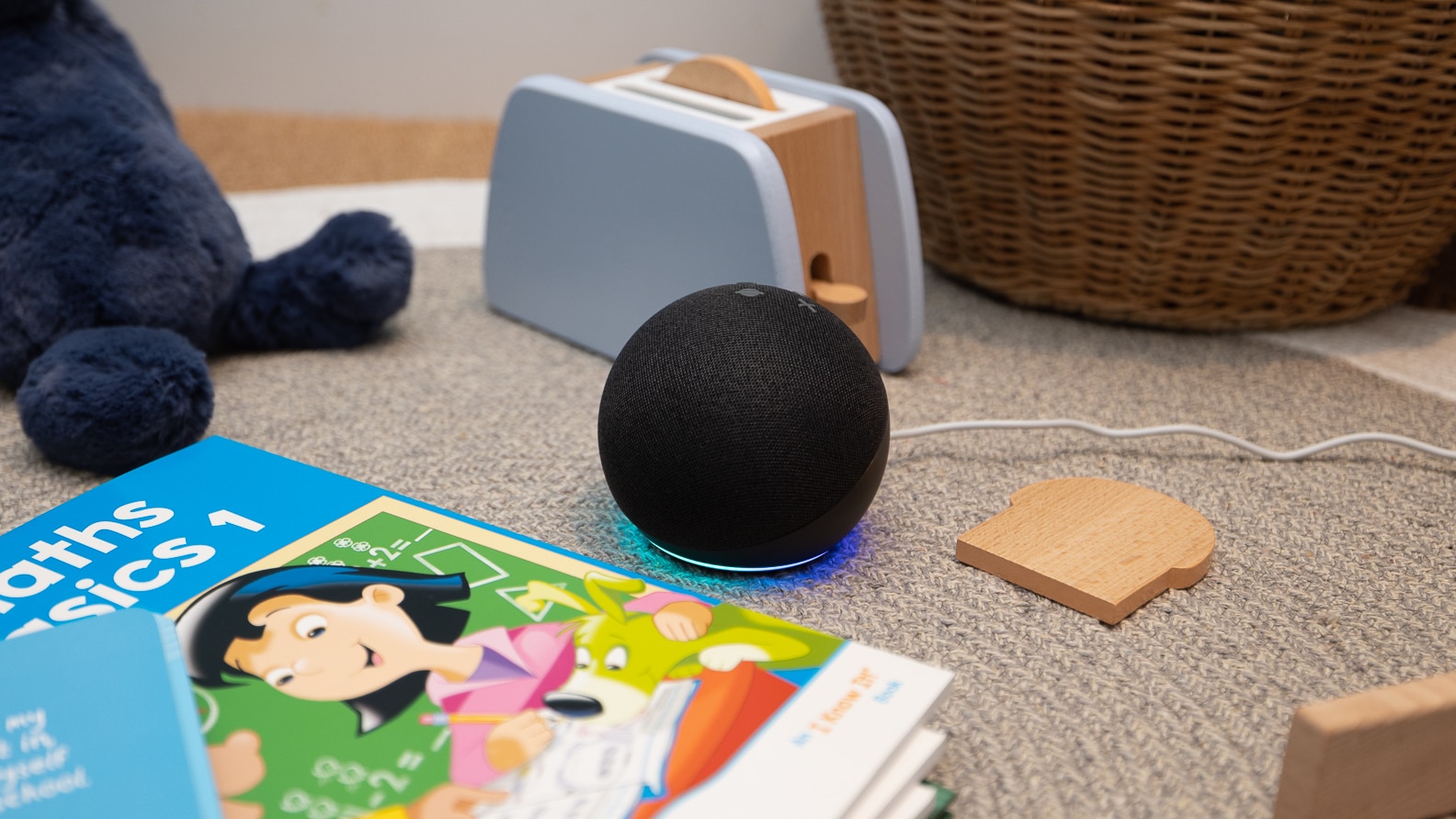 Alexa echo dot sitting on the floor, surrounded by toys and books