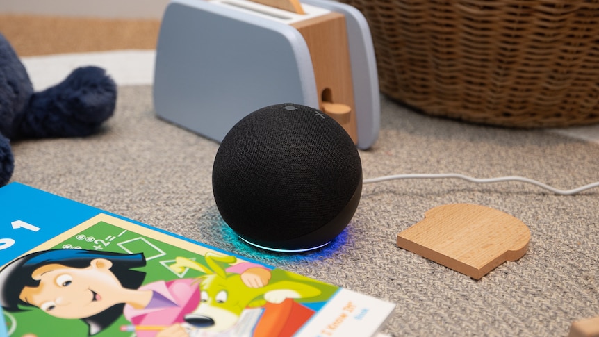 Alexa echo dot sitting on the floor, surrounded by toys and books