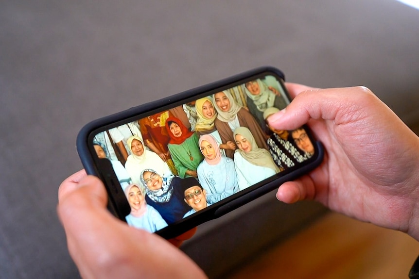 les mains tiennent un téléphone en regardant une photo de famille de femmes en Indonésie.