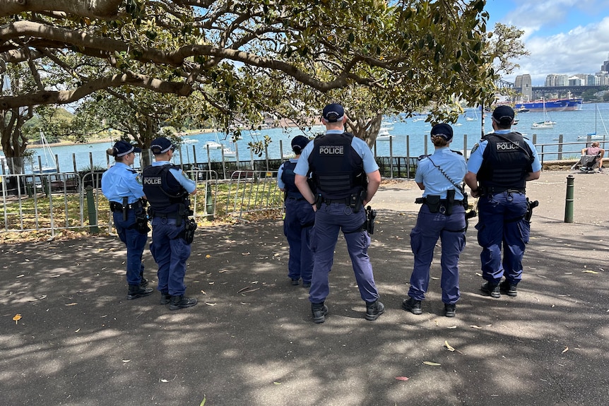 a group police women and men stand on the foreshore