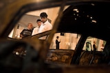 Israelis are seen through a burned car after a rocket fired from Gaza landed in Ashdod October 29, 2011