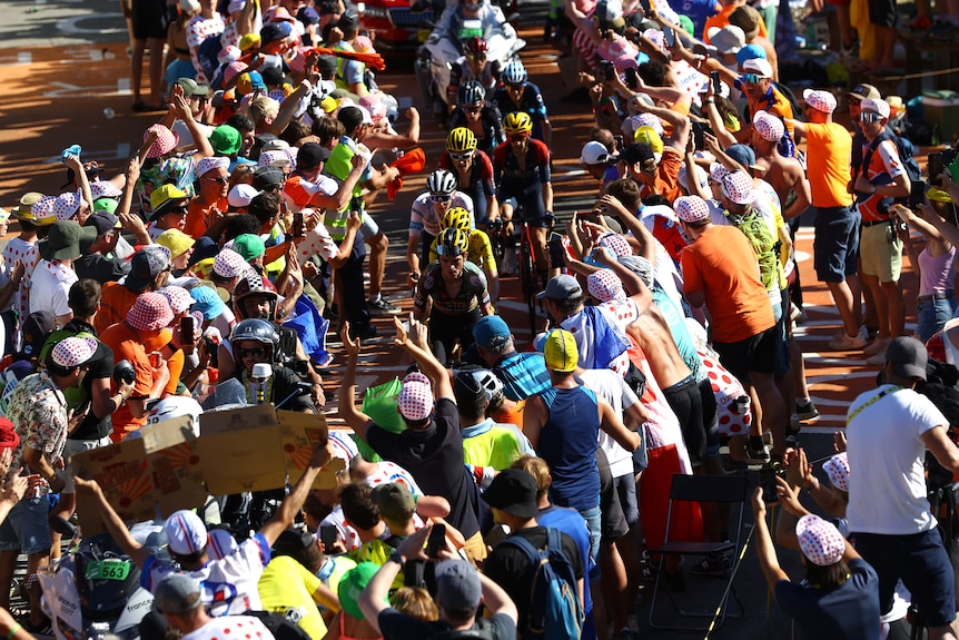 Les fans regardent des cyclistes masculins courir sur une colline