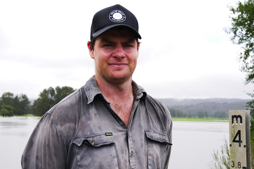 A dairy farmer with flooded paddocks in background. 