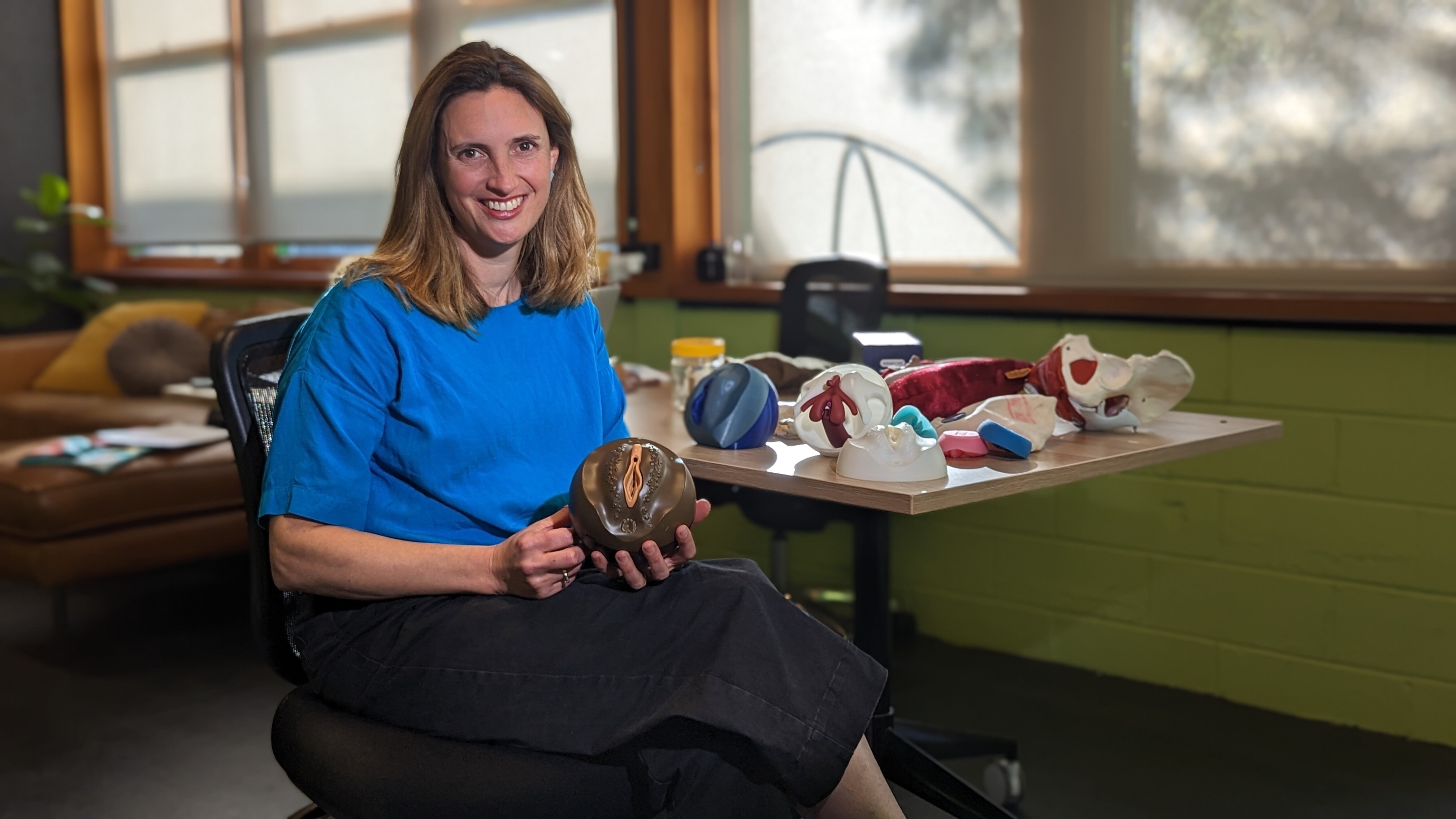 A woman holding a model of a vagina.