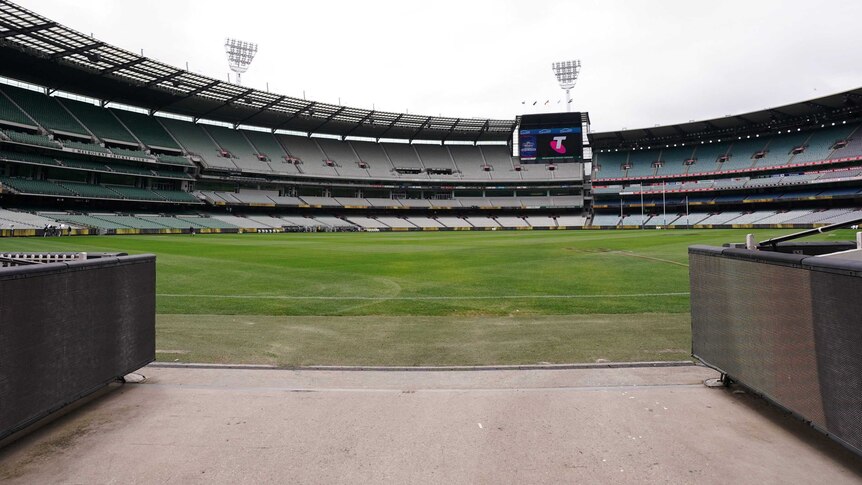 A view from a players' race at the MCG across an empty ground with scoreboard in the background.
