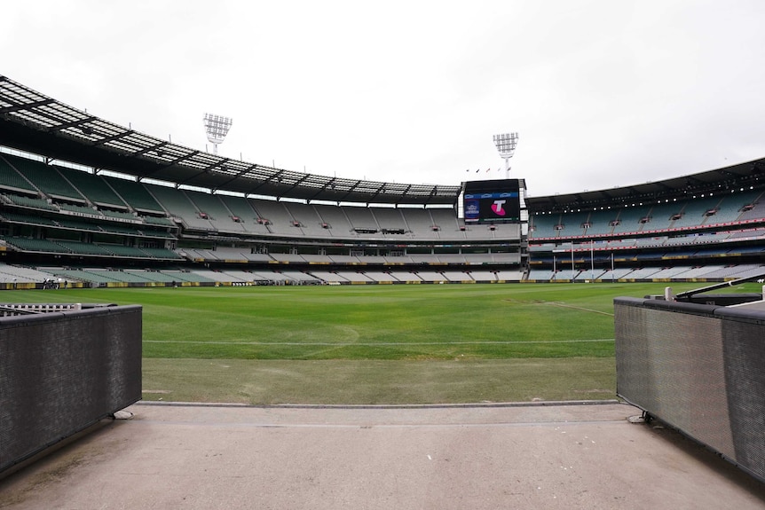 A view from a players' race at the MCG across an empty ground with scoreboard in the background.