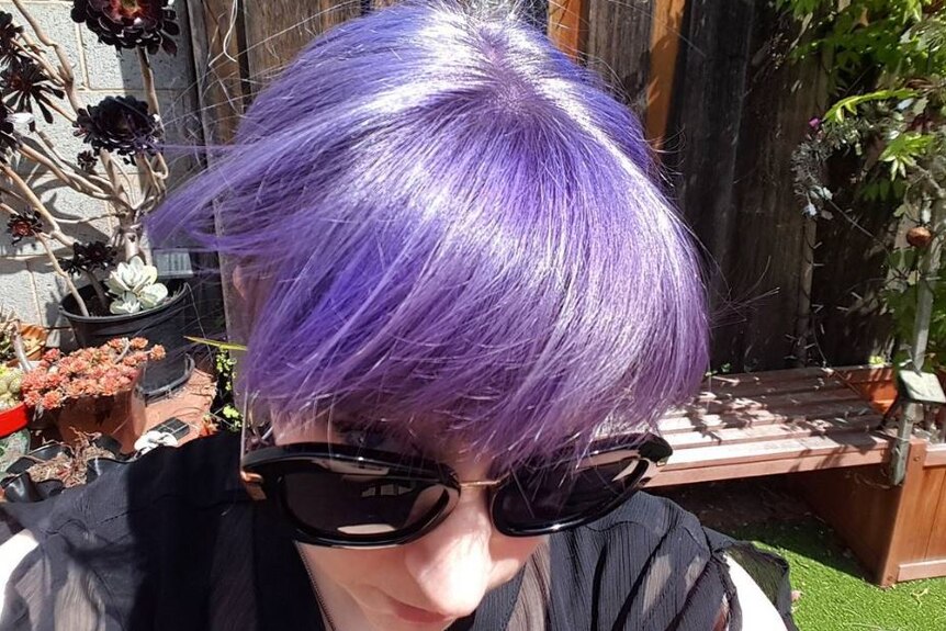 A woman wearing sunglasses with pale purple hair