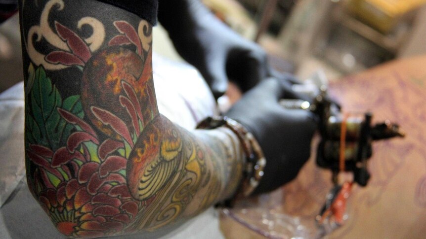 A tattooist works on a client at the SURF'n'Ink festival in Brisbane.