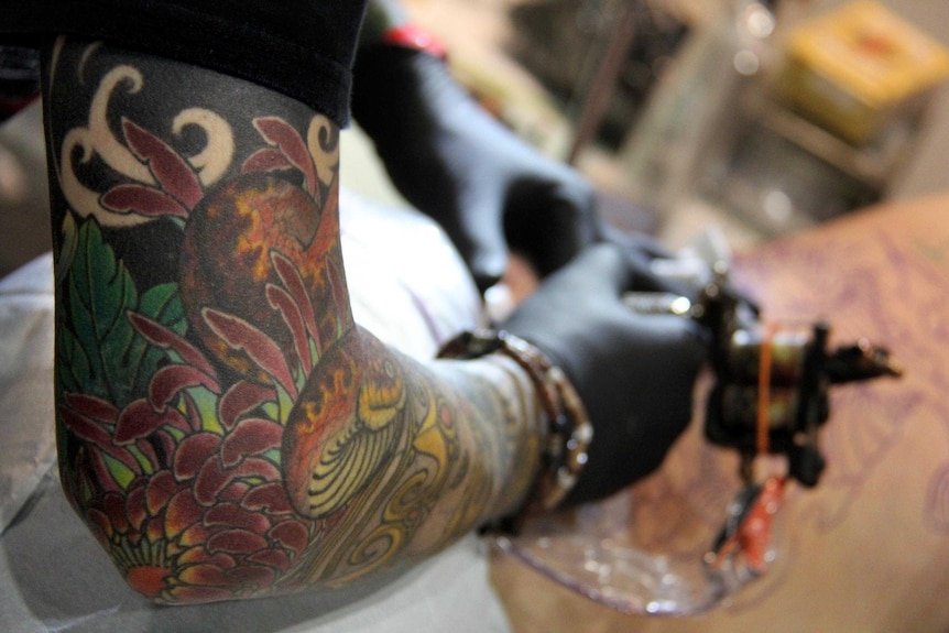A tattooist works on a client at the SURF'n'Ink festival in Brisbane.