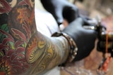 A tattooist works on a client.