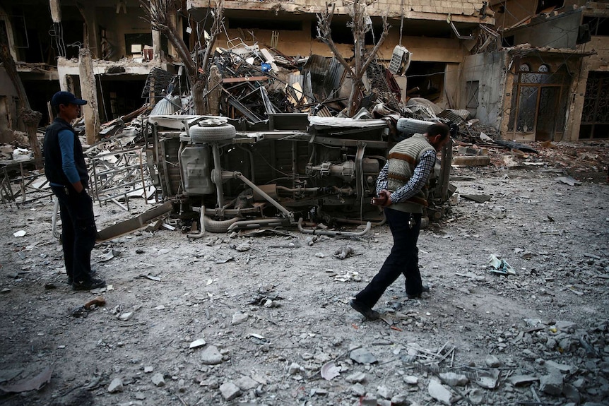 Men are seen inspecting rubble following an airstrike.