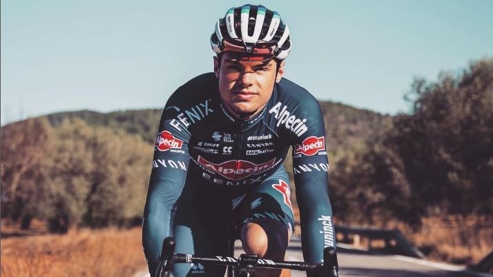 An Australian professional cyclist in team gear on the road looking straight into the camera.