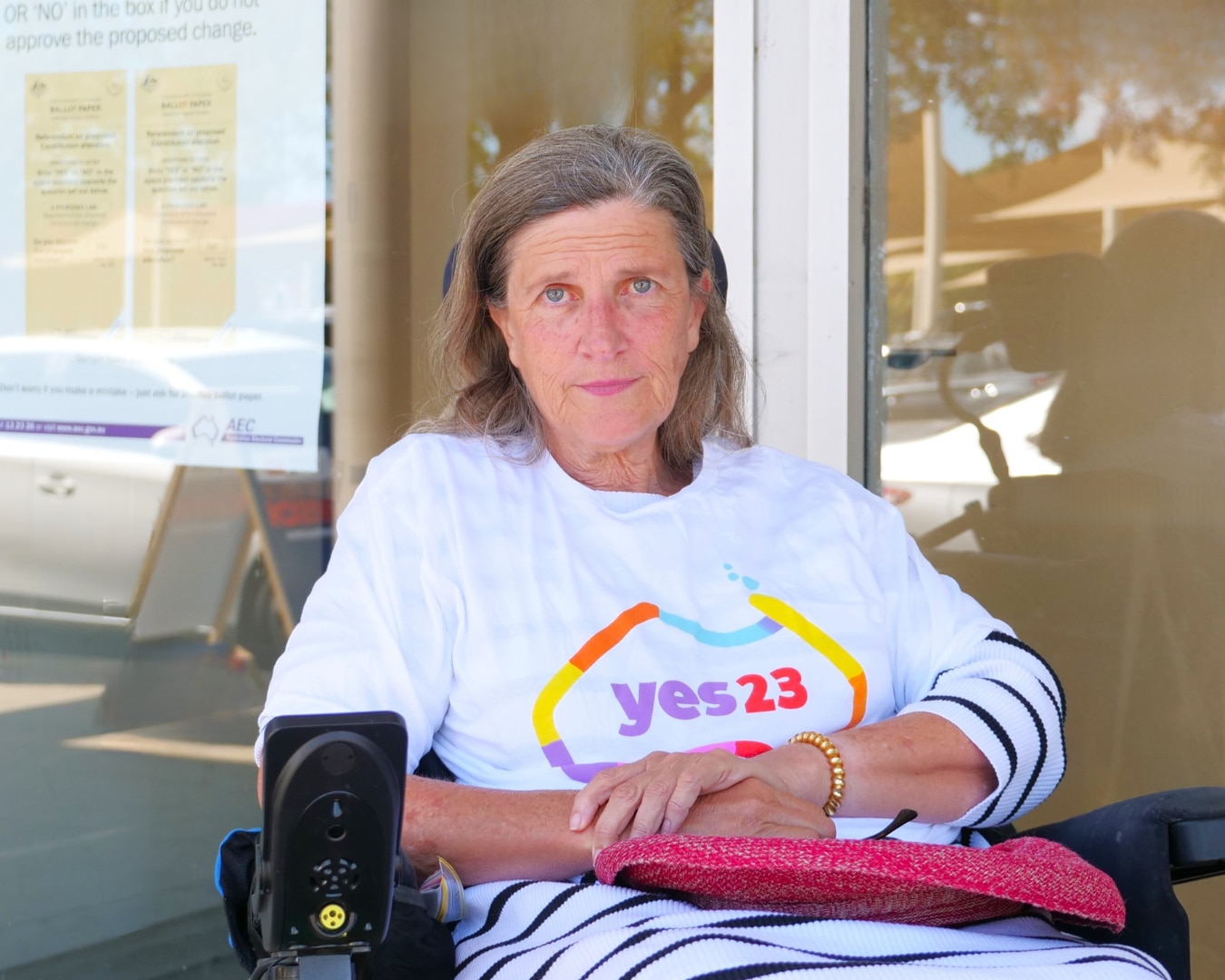 a woman sitting in an electric wheelchair outside a voting centre.