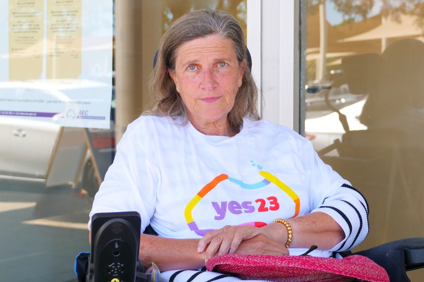 a woman sitting in an electric wheelchair outside a voting centre.