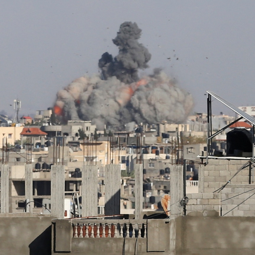 Smoke rises across a skyline and houses after a military strike