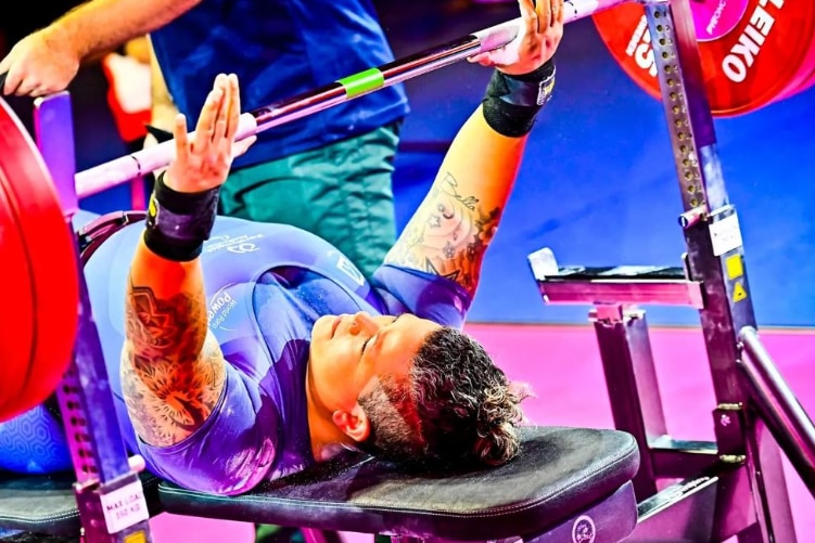 A para powerlifter lies on the bench and prepares to lift a weight.