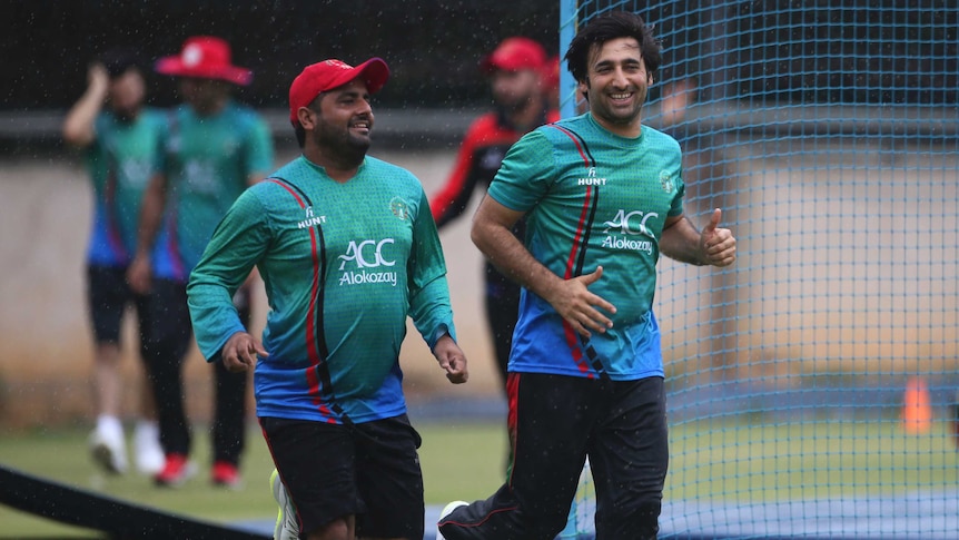 Afghanistan cricket team captain Asghar Stanikzai, right, and teammate Mohammad Shahzad run for shelter during sudden rains.