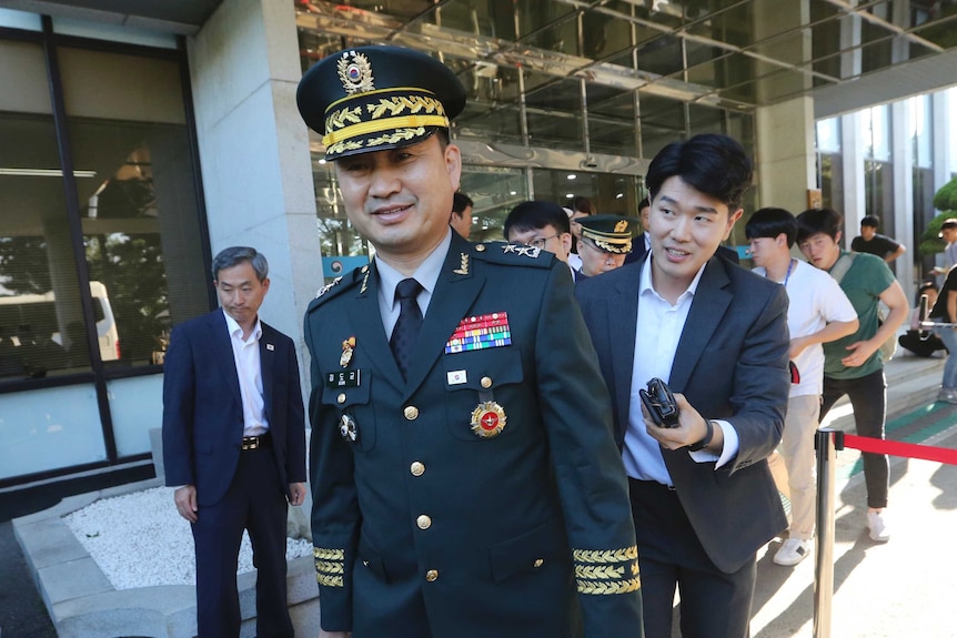 Mr Do-gyun wearing his military outfit, followed by media