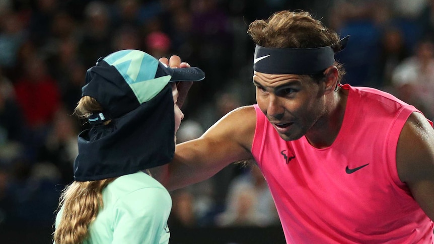 Rafael Nadal holds a ball girl on the head and looks concerned at her face