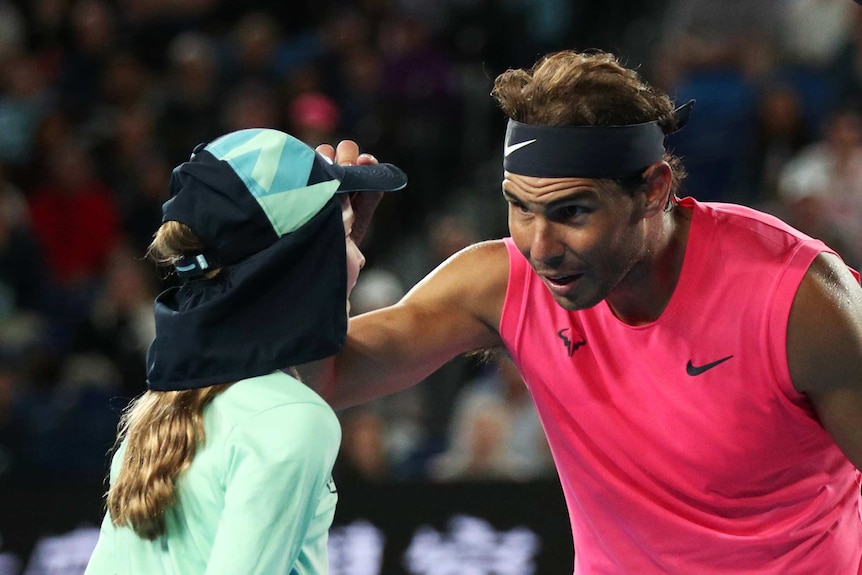 Rafael Nadal holds a ball girl on the head and looks concerned at her face