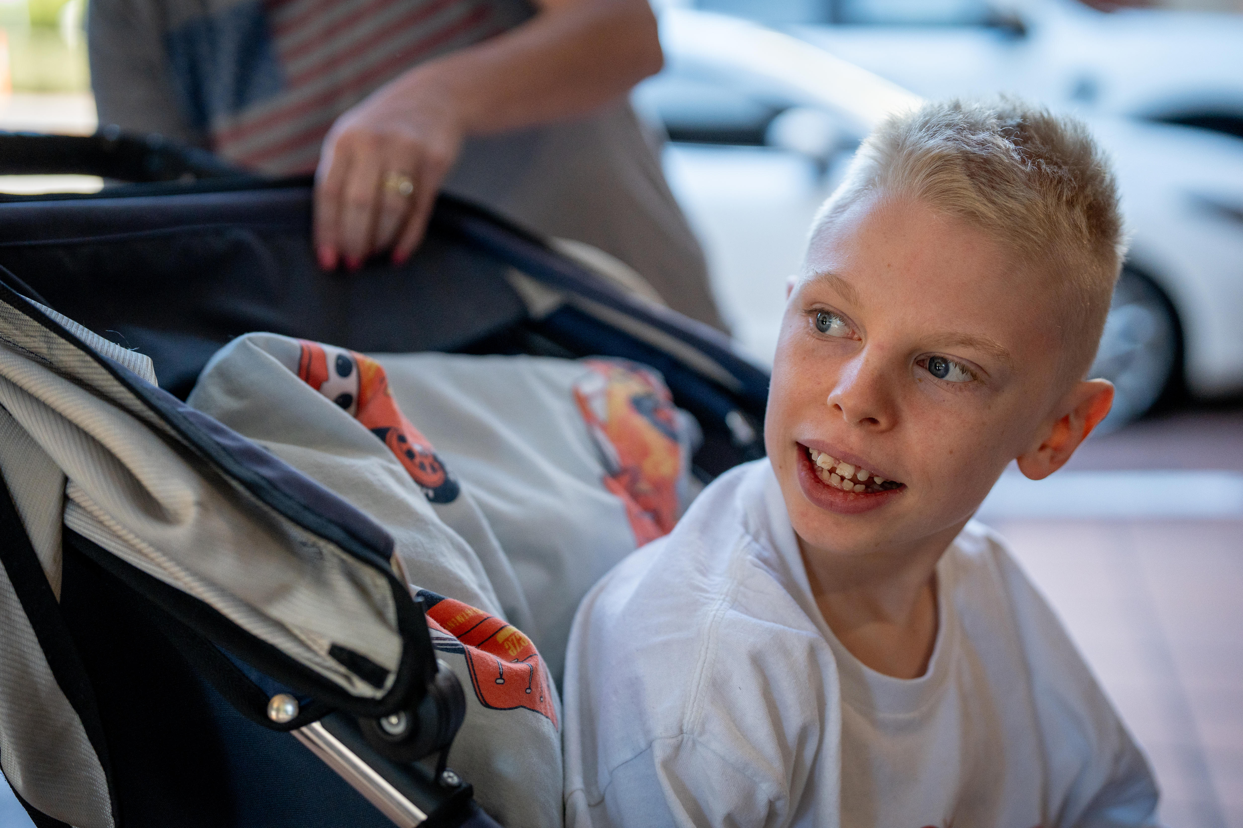  A young boy site in a pram-like mobility aid