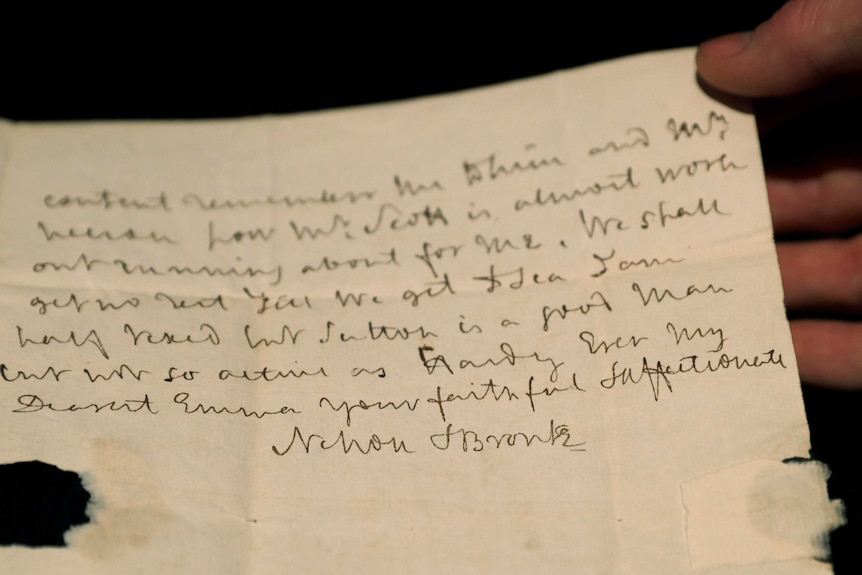 A person holds a letter on worn paper written by Lord Nelson.