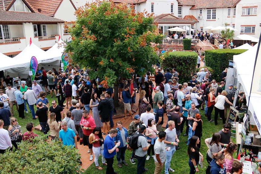 A beer garden lined with stalls and packed with people.