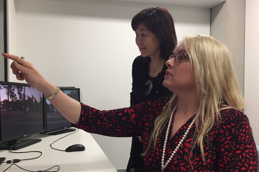Dr Bridie Scott Parker points at a series of screens as Dr Bonnie Huang stands behind her looking on