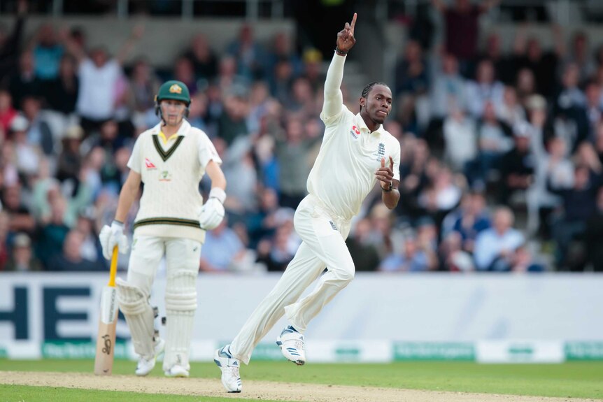 Jofra Archer points his right index finger to the sky while running.