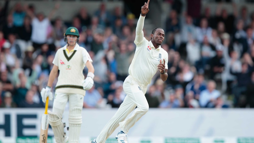 Jofra Archer points his right index finger to the sky while running.