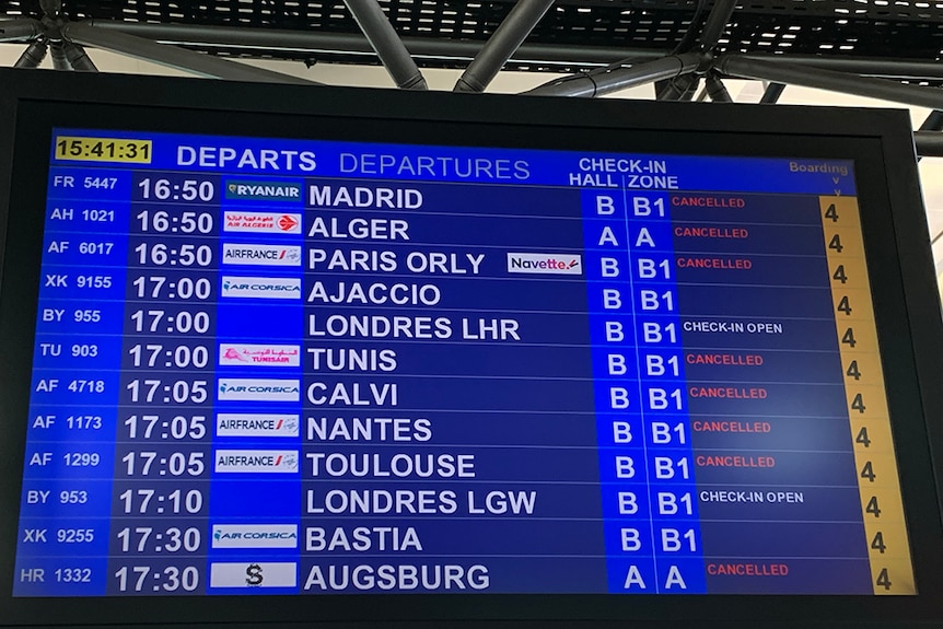 An airport departures board showing many cancelled flights.