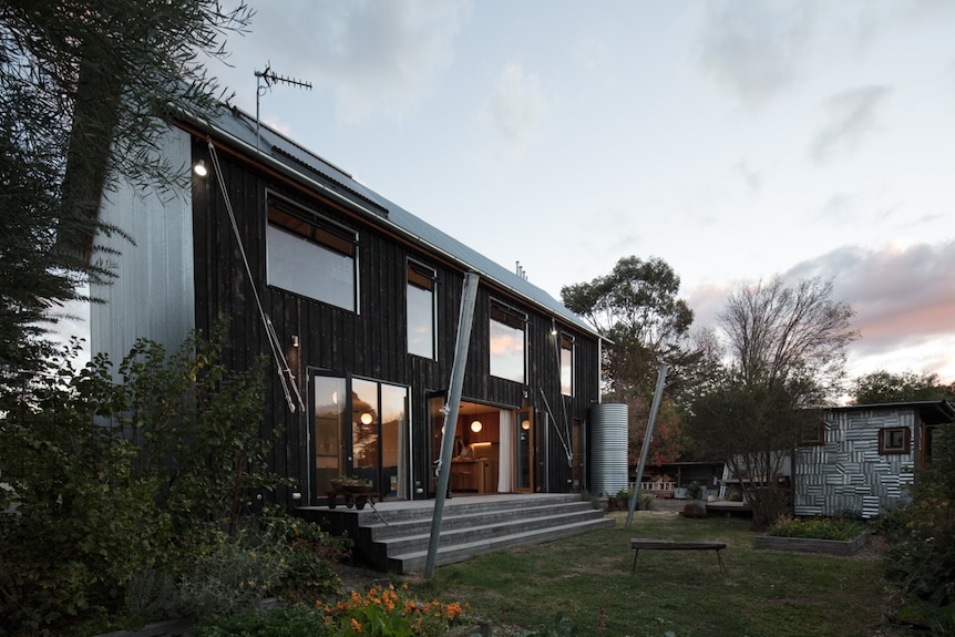 The back view of a two-storey house, featuring charred timber cladding.