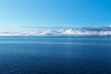 The ocean with clouds looking like hills or mountains in the distance