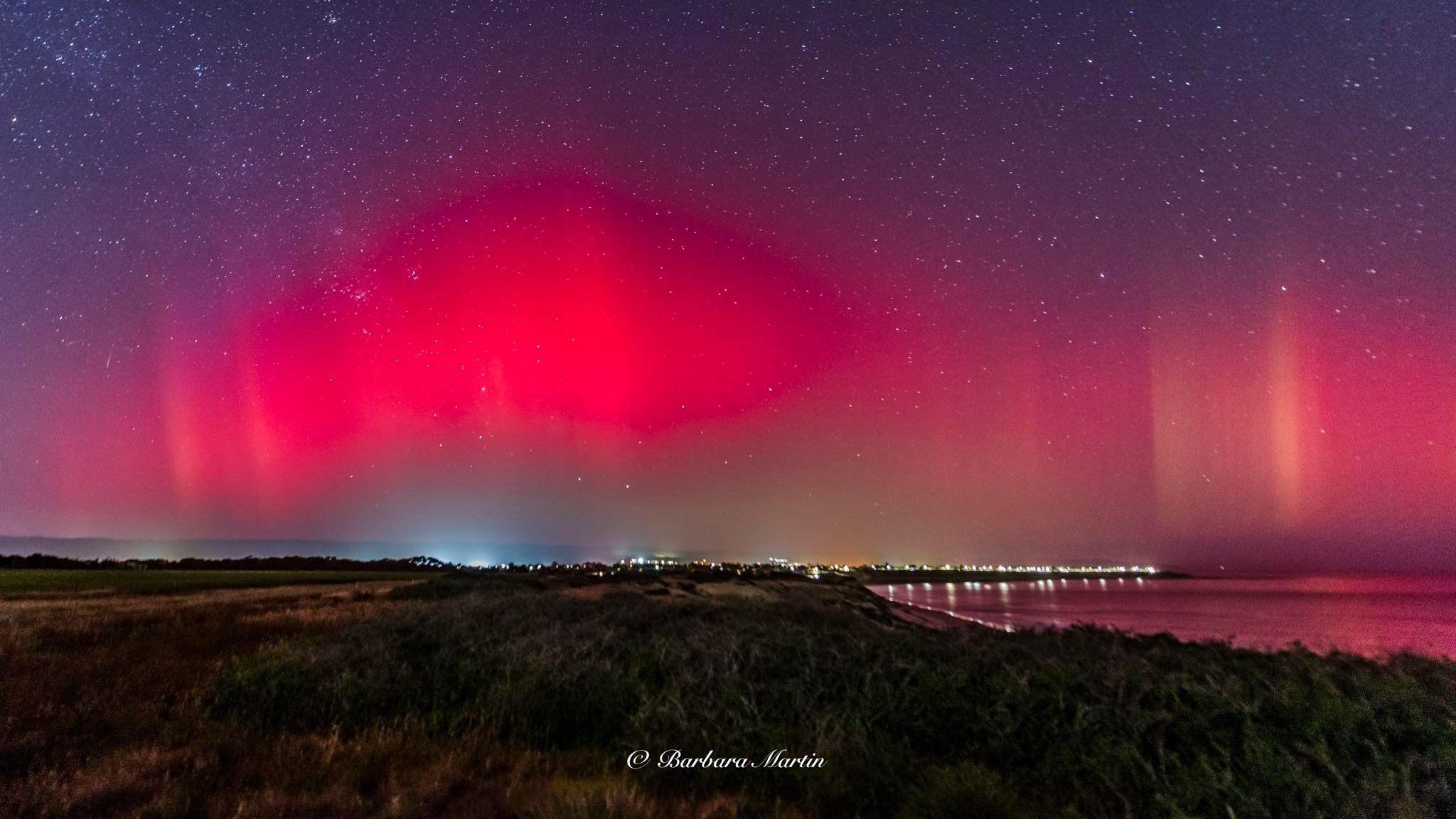 A very bright pink and red aurora in the night sky