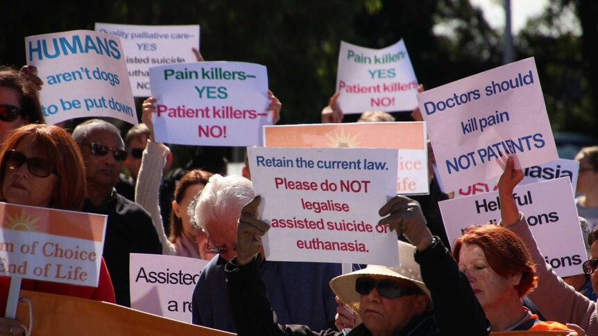 People hold signs opposing euthanasia at a rally.