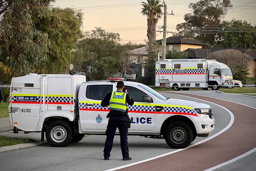 A police ute parked sideways across a suburban street with a police incident truck in the background.