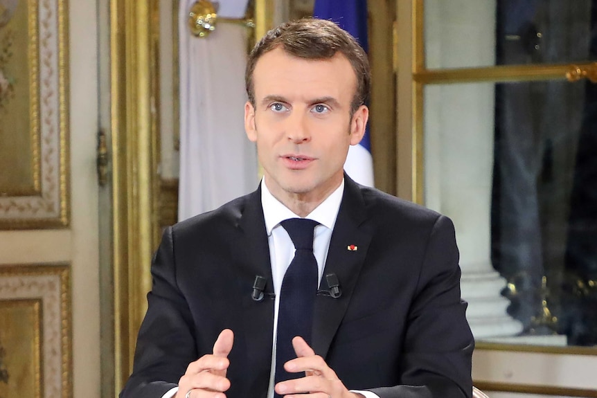 Emmanuel Macron gestures with his hand while making a national address.