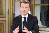 Emmanuel Macron gestures with his hand while making a national address.