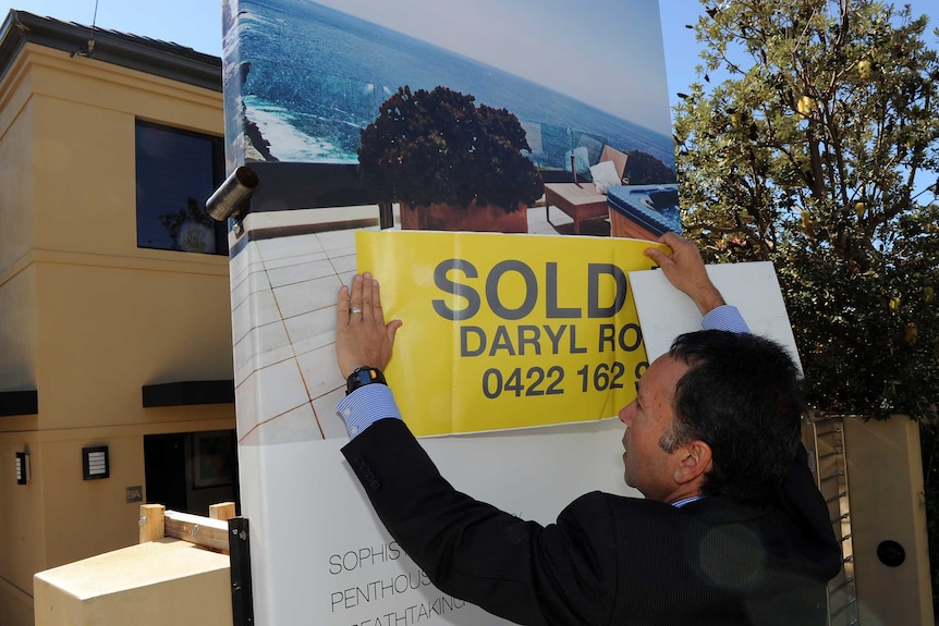 Real estate agent with sold sign