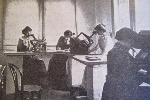 Black and white photo of four women examining photographic plates using measuring devices