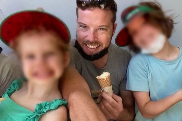 A man eating ice cream with his two young children.