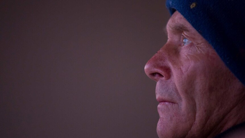 Tony Symes' beanie-clad head in profile as he looks skyward, eyes on the lighthouse.