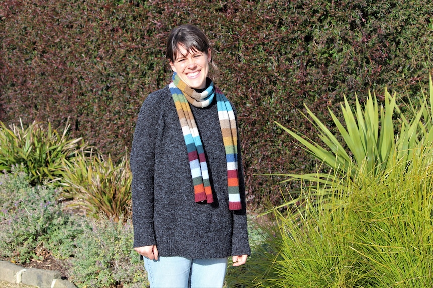 A woman wearing a scarf and woollen jumper. 