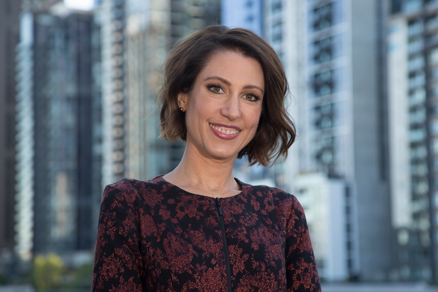 Tamara Oudyn stands in front of a Melbourne skyscape.