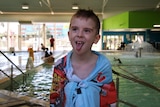 Kiedis sticks his tongue out, wrapped in a towel in front of a pool.