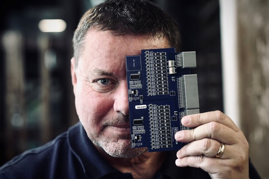 a man with a electronics chip board in front of his face