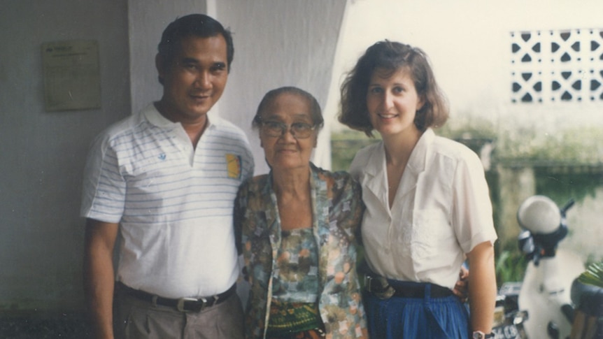 A man and two women embracing each other while smiling to the camera.