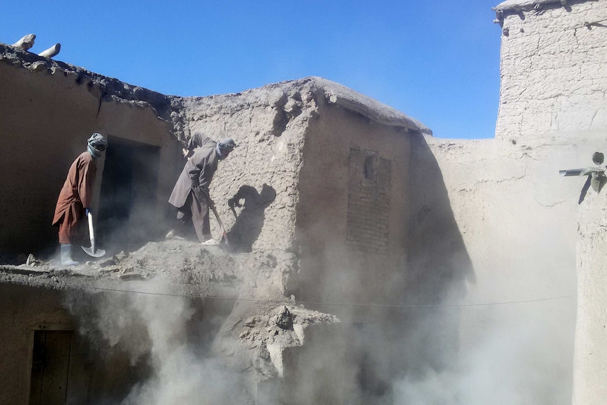 Afghan men clear rubble of an earthquake-damaged house