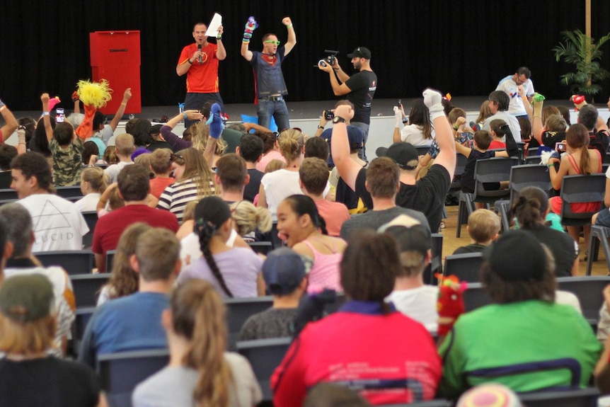 A group of people wearing sock puppets celebrate with their hands in the air